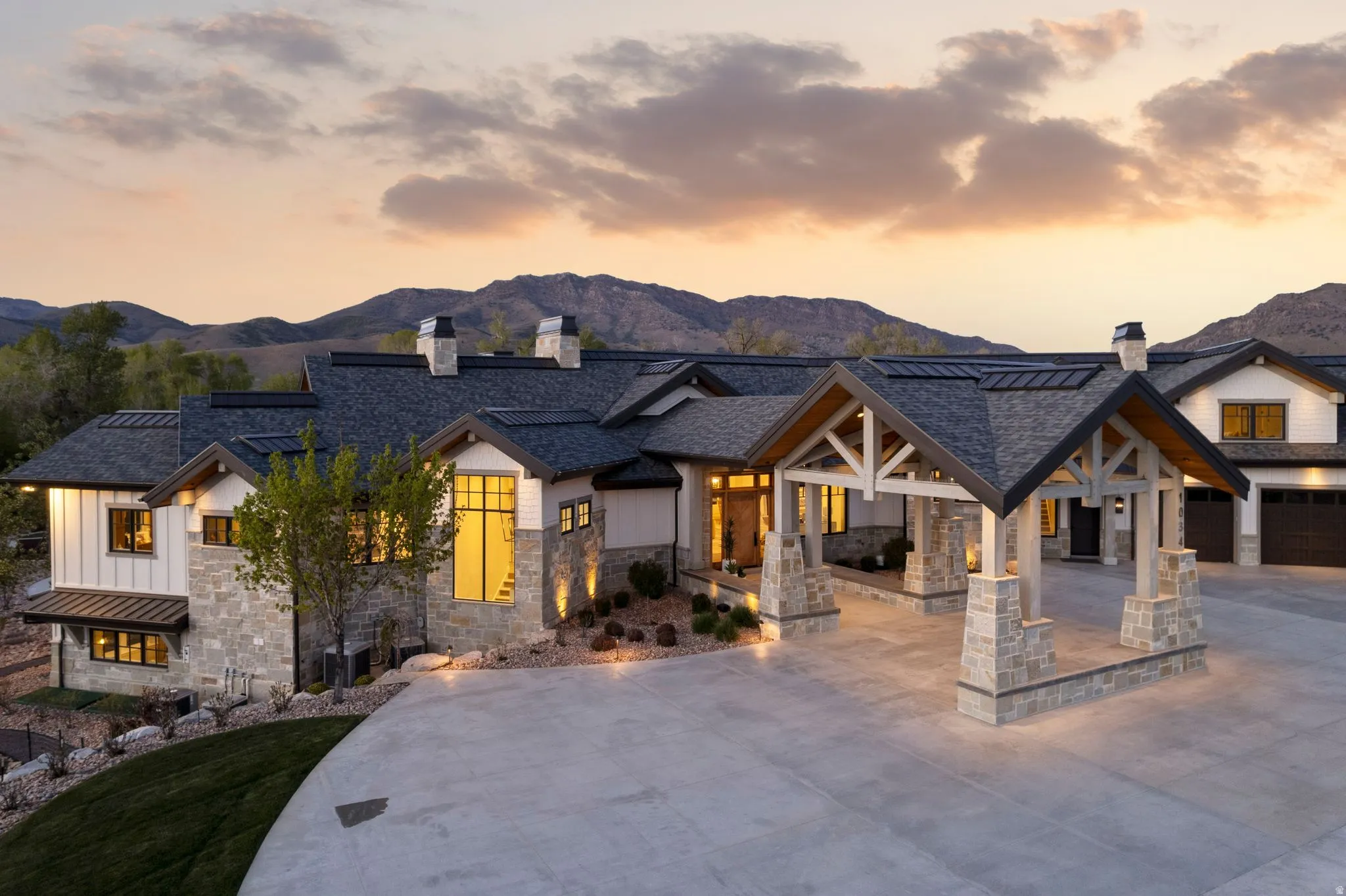 Modern inspired farmhouse featuring a chimney, driveway, stone siding, a mountain view, and a garage