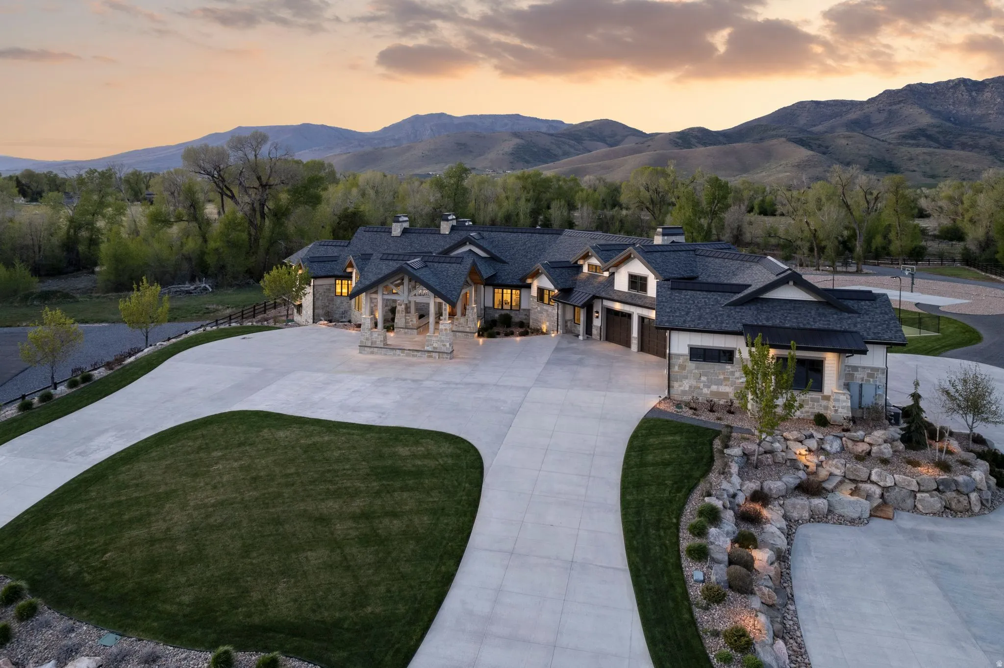 View of front of property featuring stone siding, a chimney, concrete driveway, and a mountain view