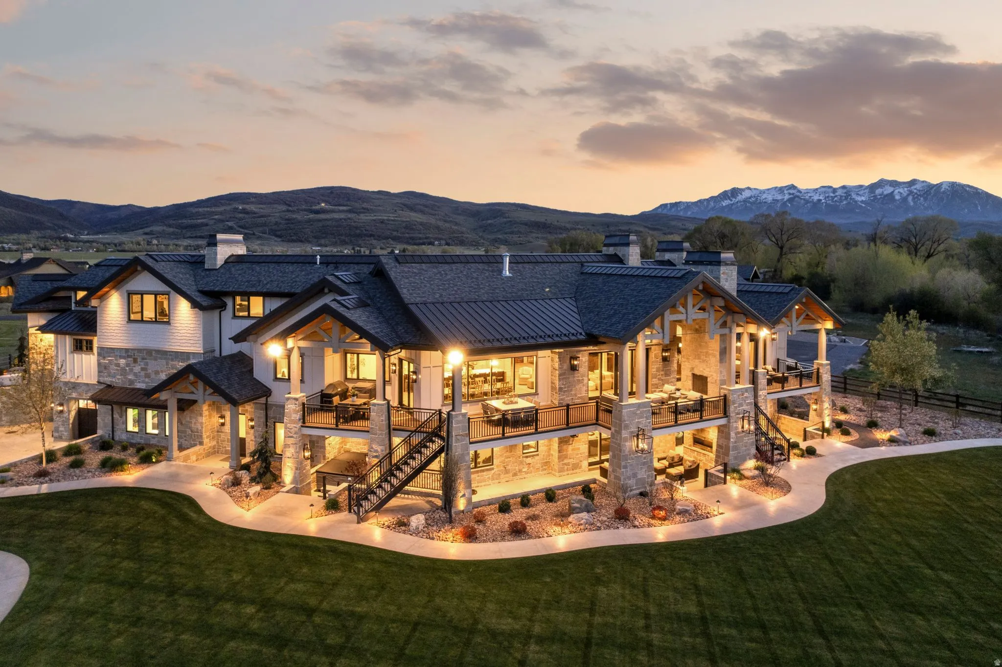 Back of property at dusk with a chimney, stone siding, and a mountain view