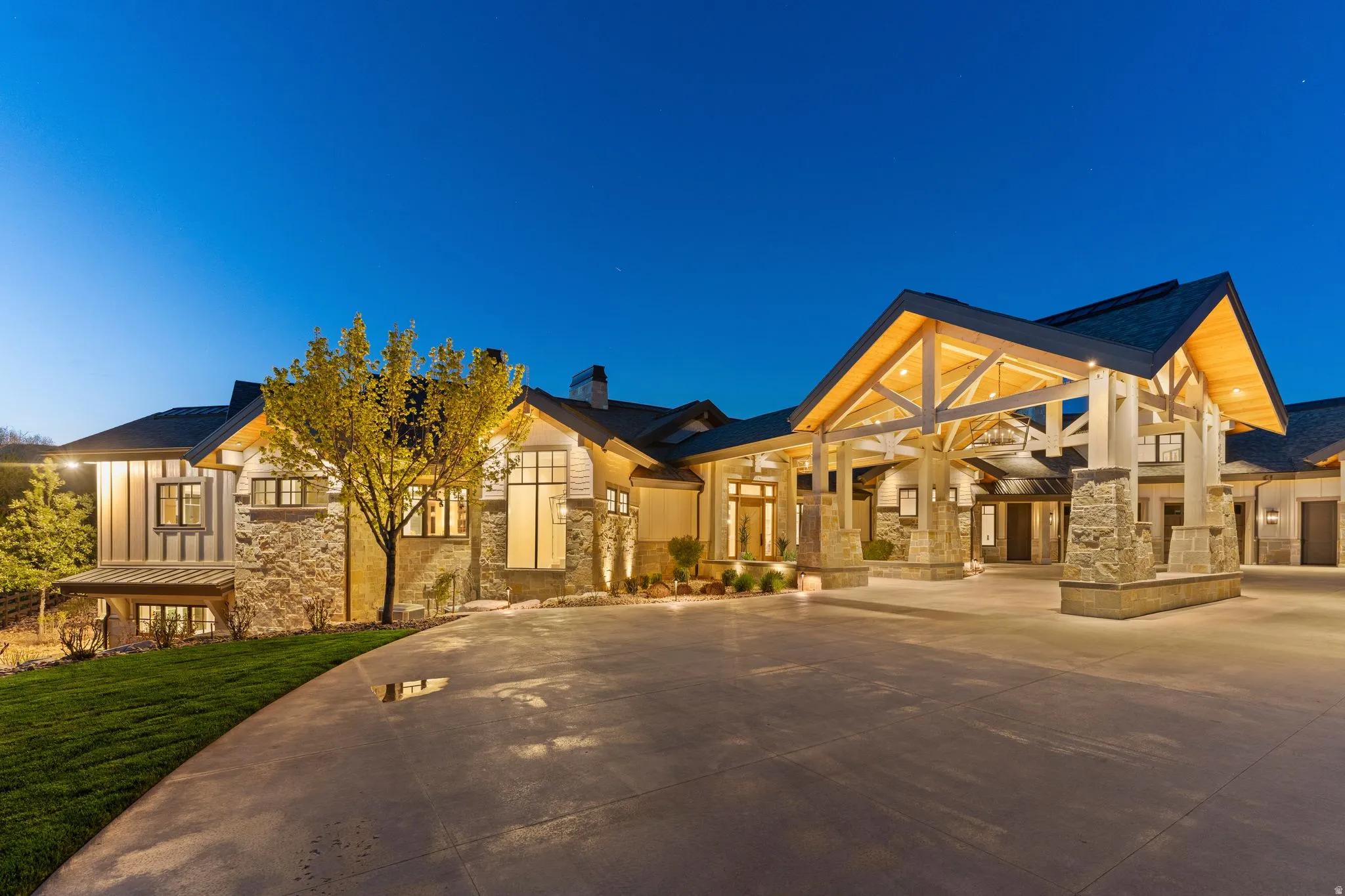 Modern farmhouse style home featuring stone siding, concrete driveway, and a chimney