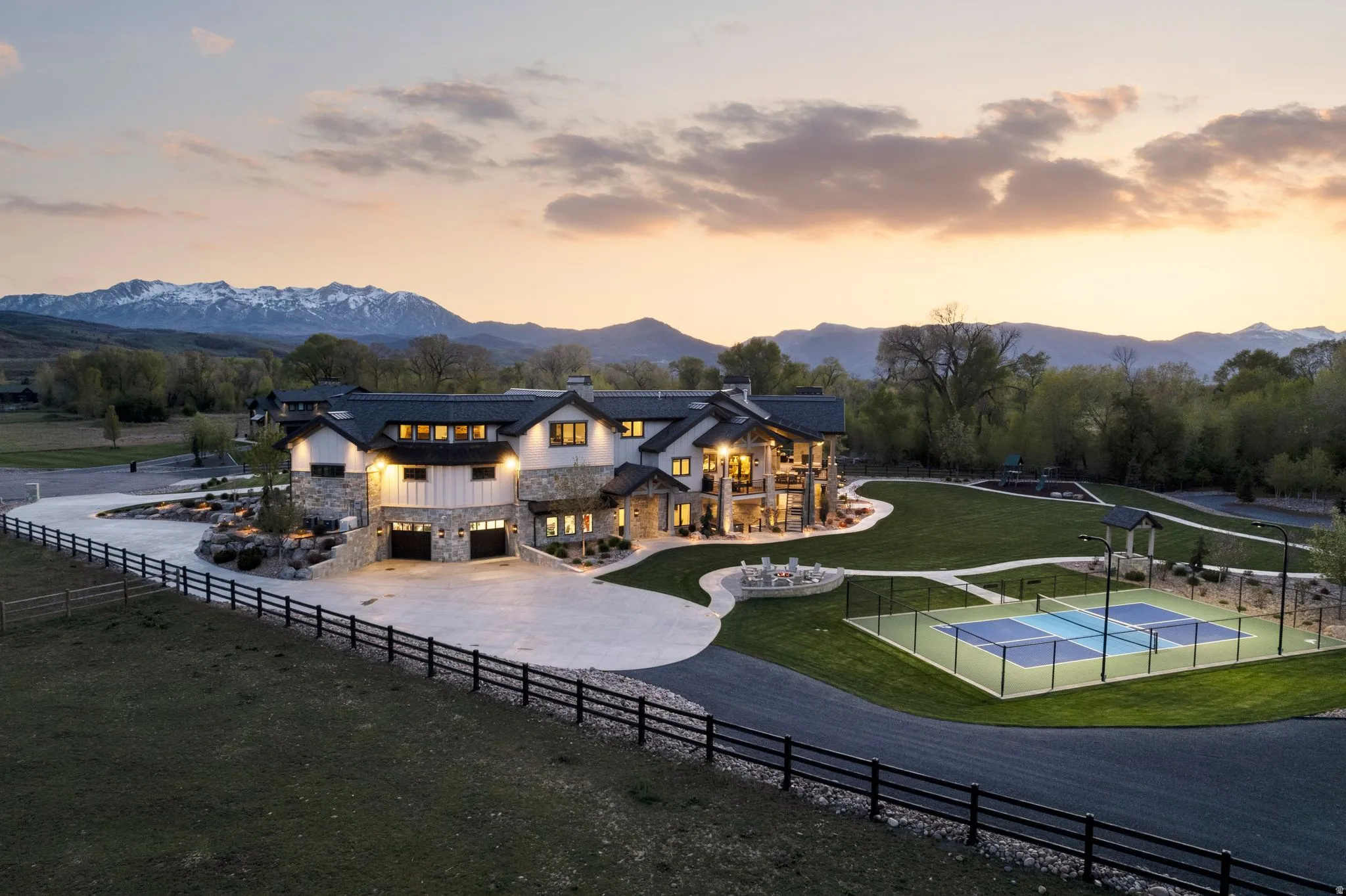Rear view of property with stone siding, a chimney, a tennis court, a garage, and a mountain view