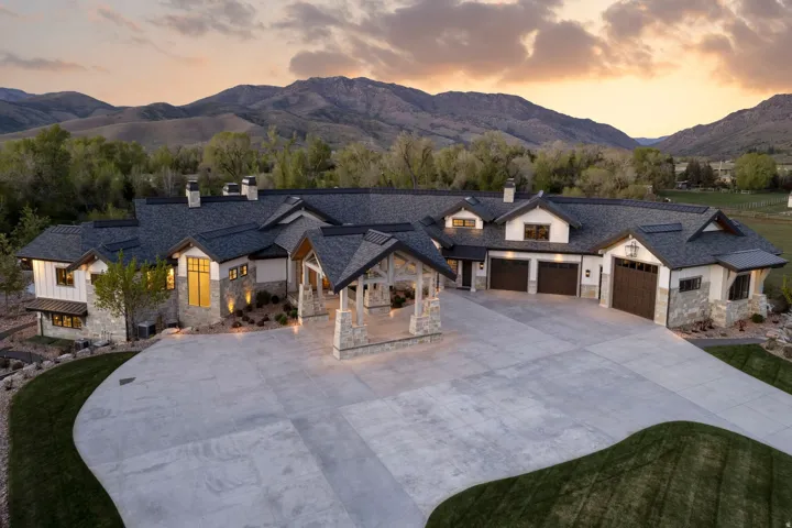 View of front facade with a chimney, a mountain view, concrete driveway, a garage, and stone siding