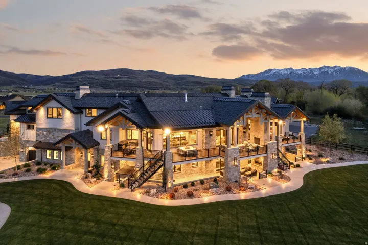 Back of property at dusk with a chimney, stone siding, and a mountain view