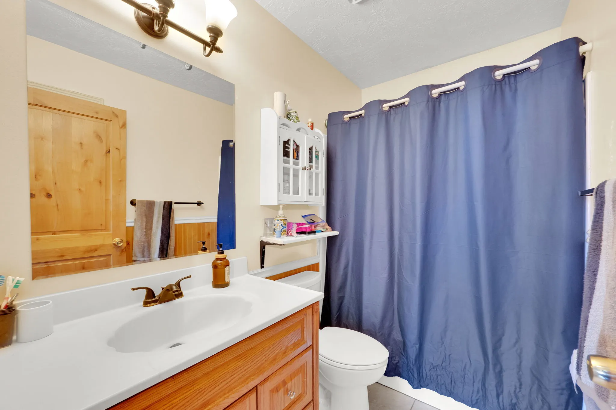 Bathroom with vanity, light tile patterned flooring, and shower / bath combo with shower curtain