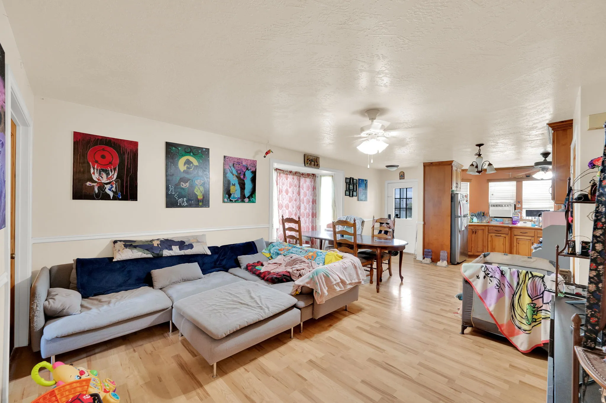 Living area featuring light wood-style flooring, a ceiling fan, and a textured ceiling