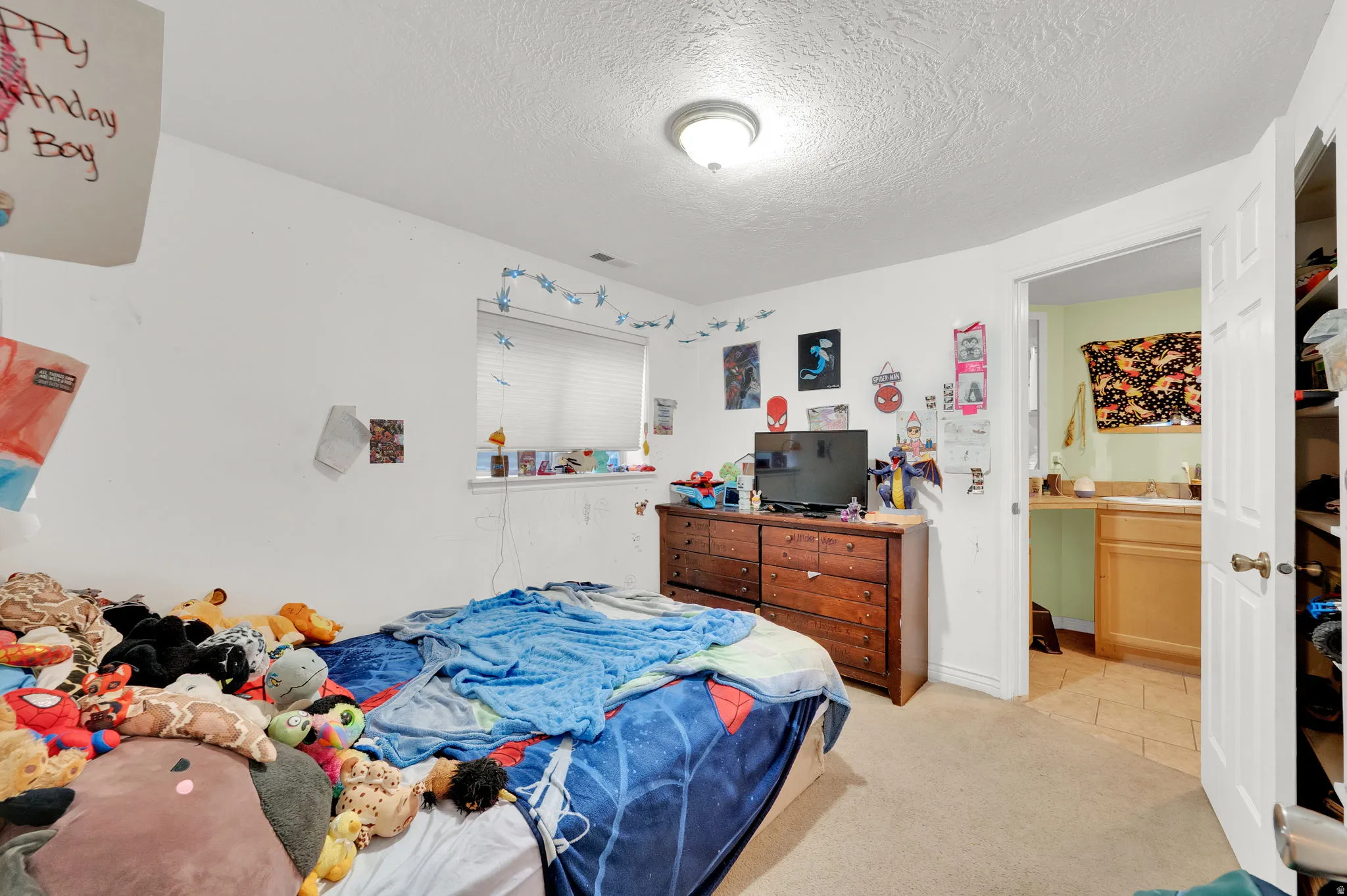 Bedroom with a textured ceiling and light carpet