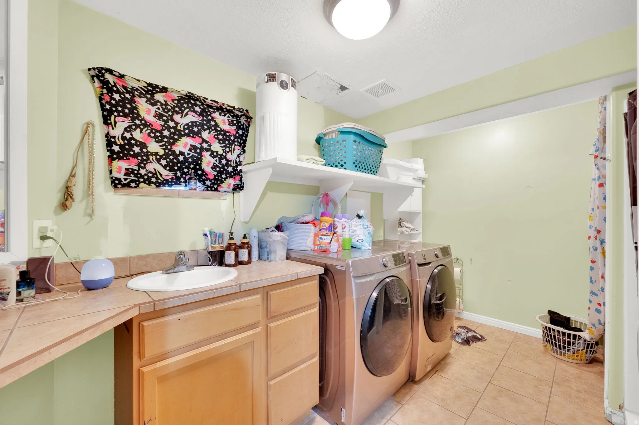 Laundry area with washing machine and dryer and light tile patterned floors