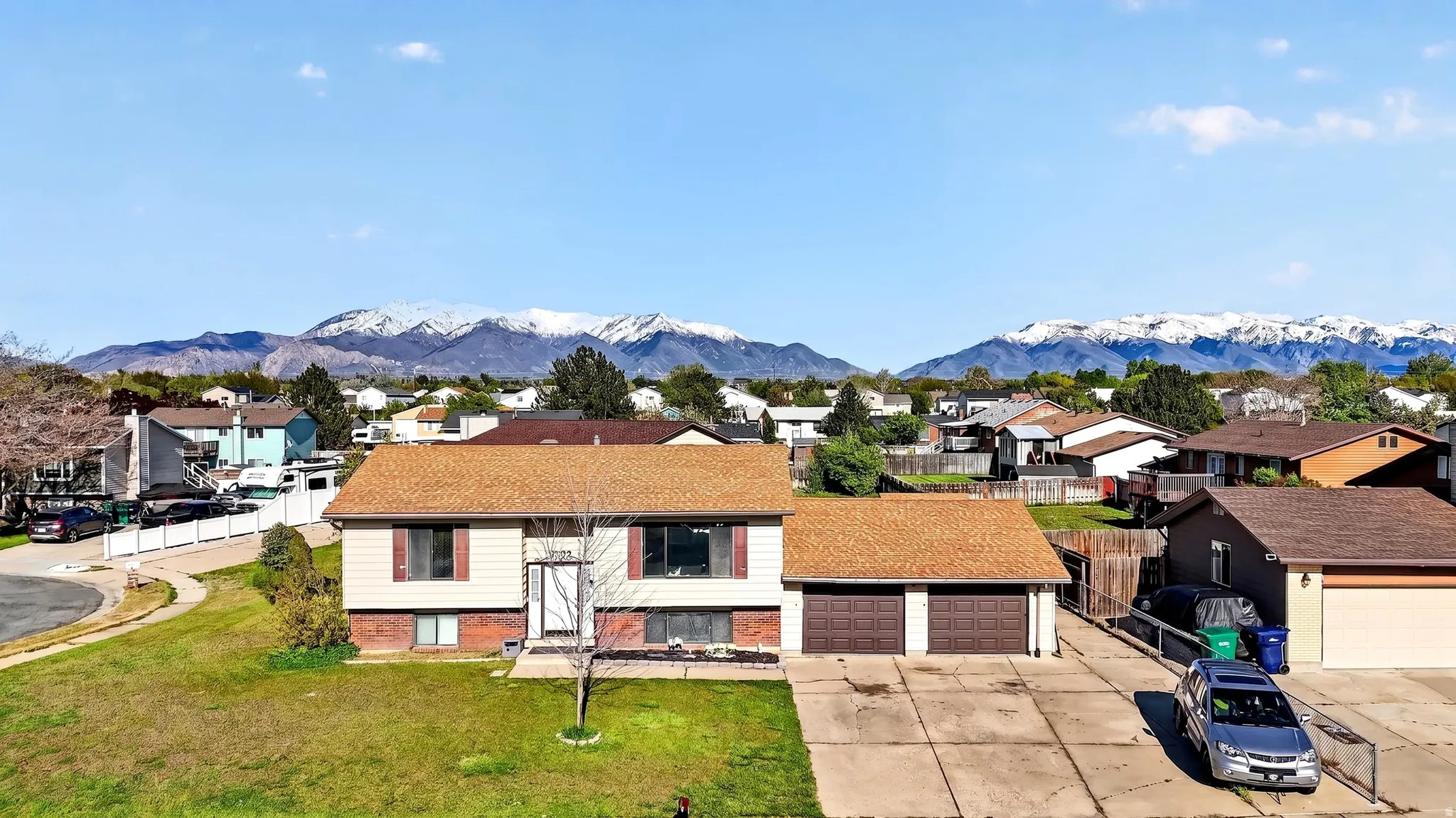 Raised ranch featuring brick siding, a mountain view, a residential view, a front lawn, and concrete driveway