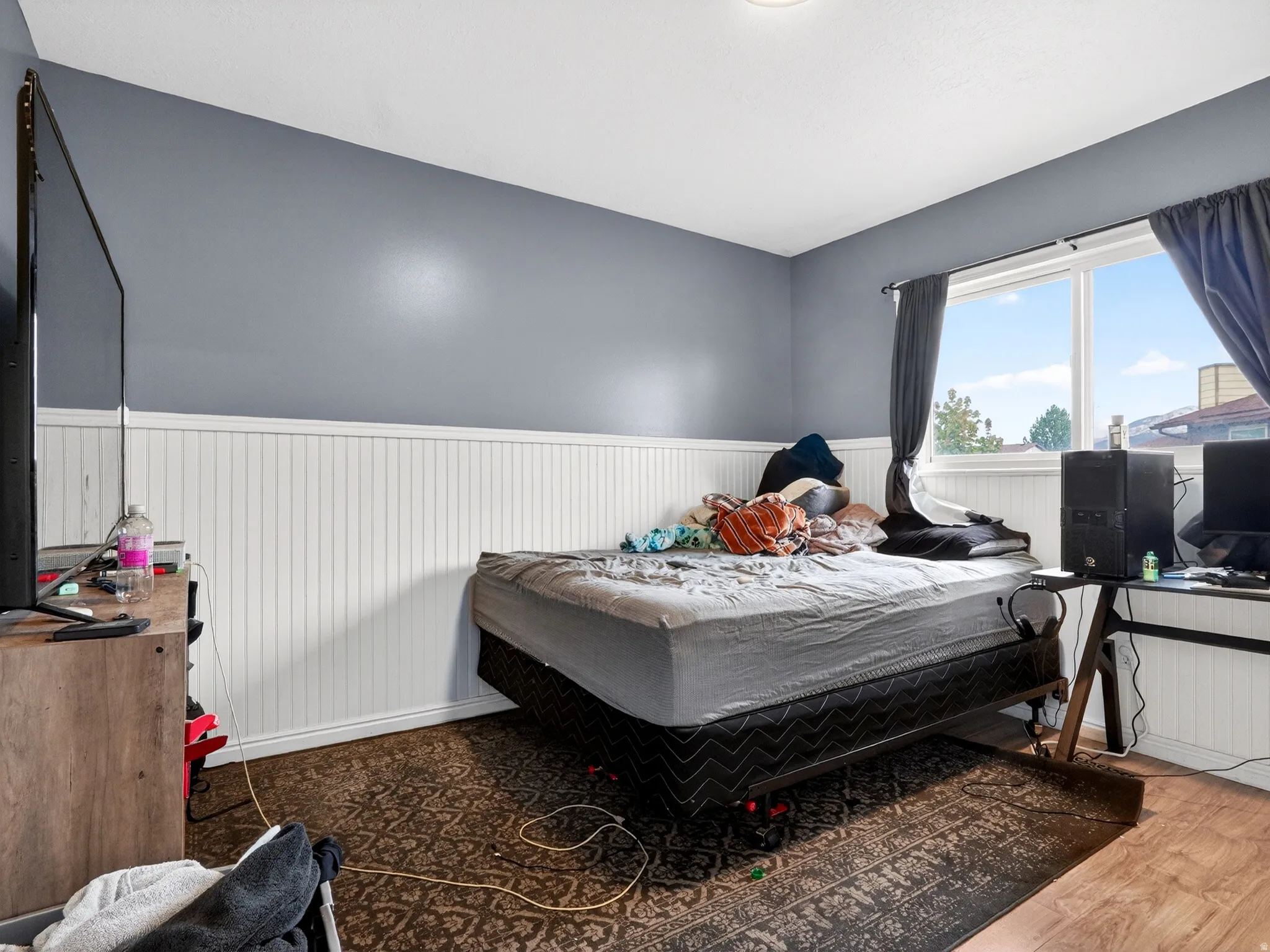 Bedroom featuring wood finished floors and a wainscoted wall