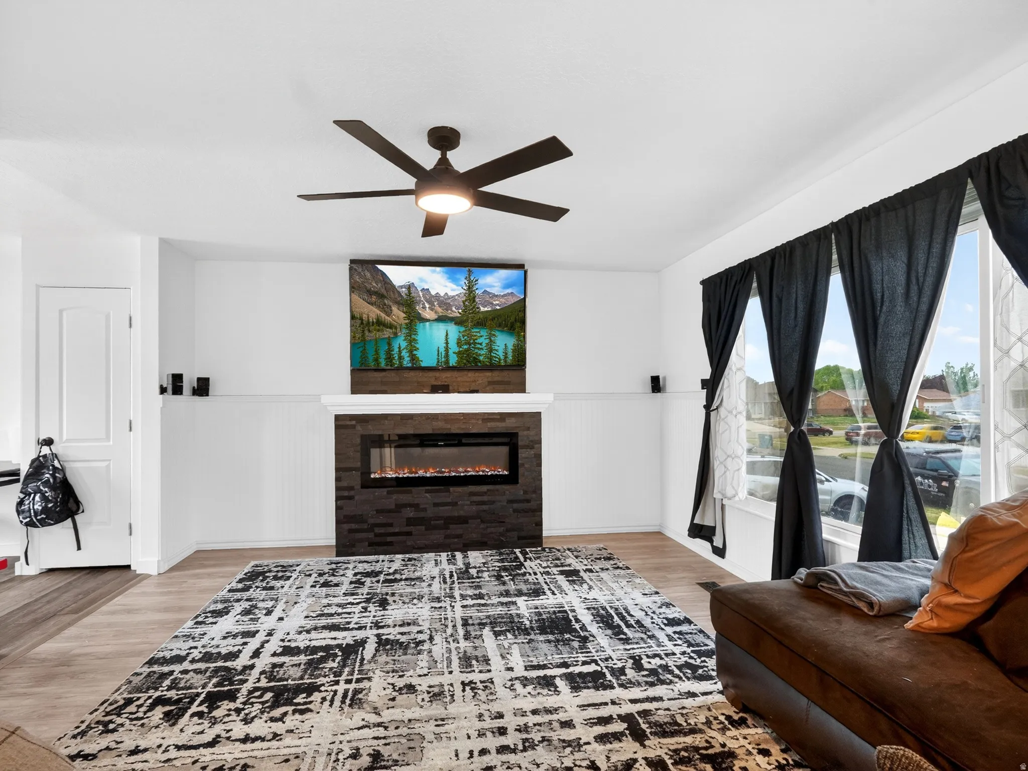 Living room featuring a glass covered fireplace, light wood finished floors, and ceiling fan