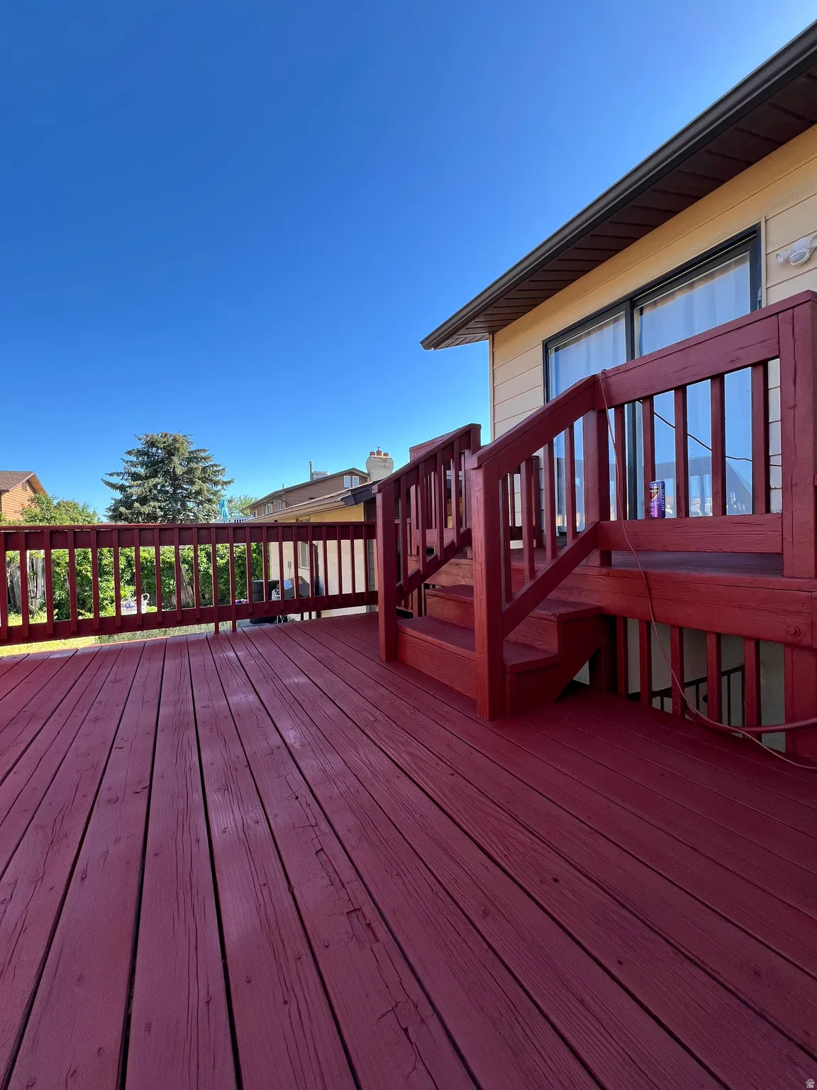 Spacious outdoor deck with a vibrant red finish, featuring an integrated staircase and matching railings