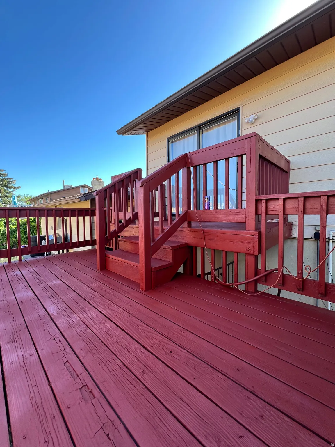 Expansive red-stained deck featuring a multi-level design and railings