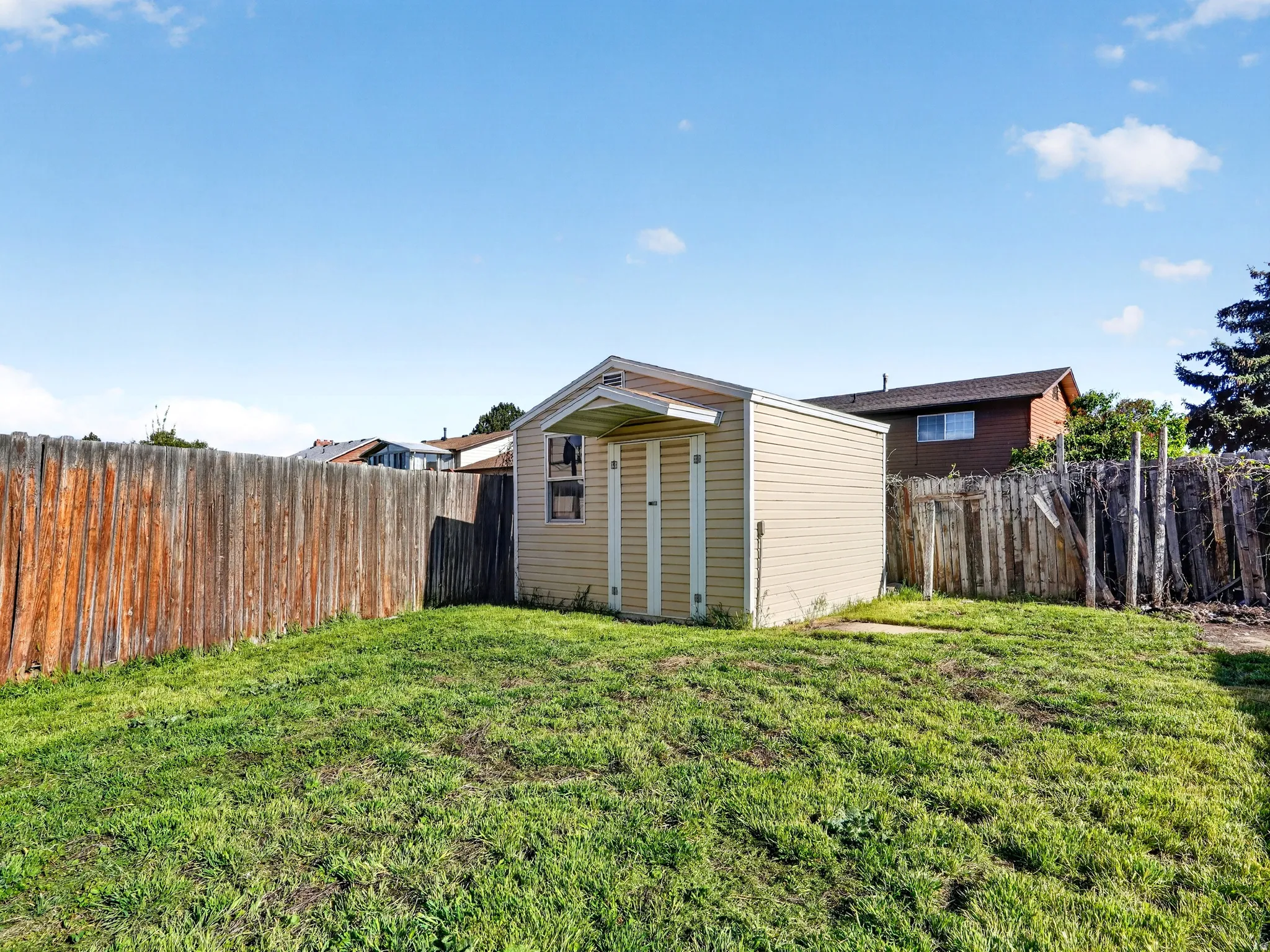 Fenced backyard featuring a storage shed