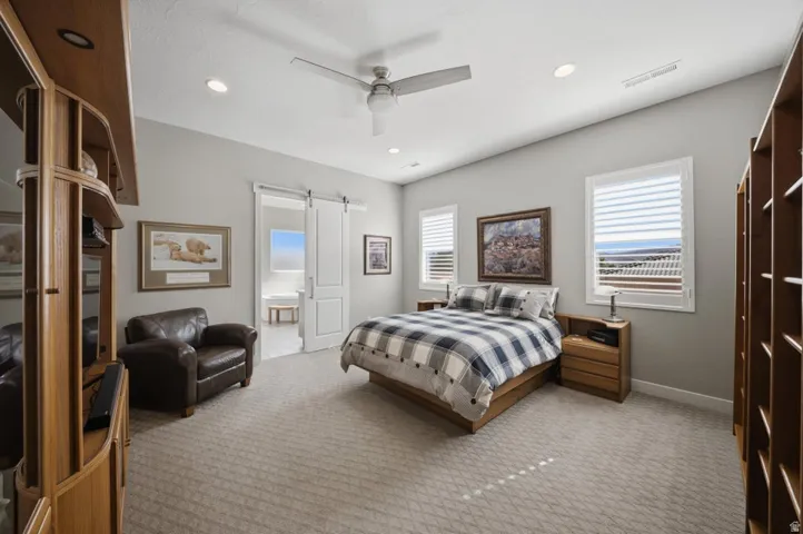 Bedroom with carpet floors, ceiling fan, a barn door, recessed lighting, and ensuite bath