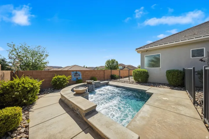 View of pool featuring an in-ground hot tub, a fenced backyard, and patio surround