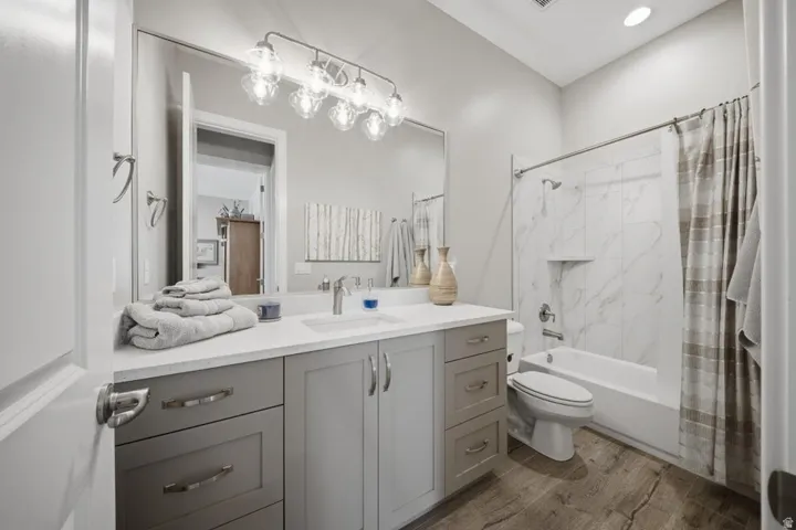 Bathroom featuring vanity, shower / tub combo, light wood finished floors, and recessed lighting