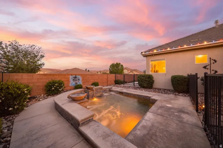 Pool at dusk featuring an in-ground hot tub, a fenced backyard, and a patio area