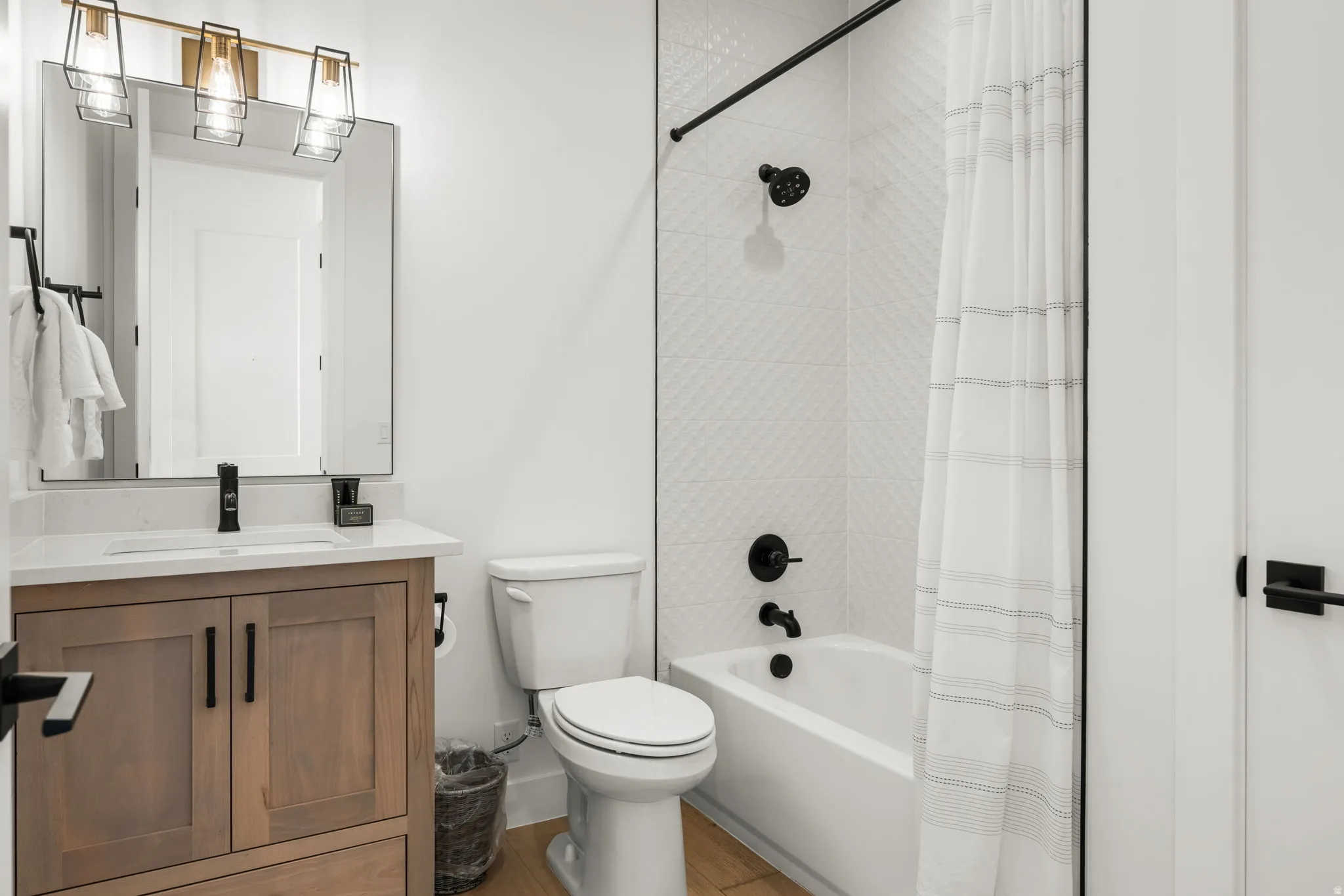 Bathroom featuring vanity, shower / tub combo with curtain, and light wood-type flooring
