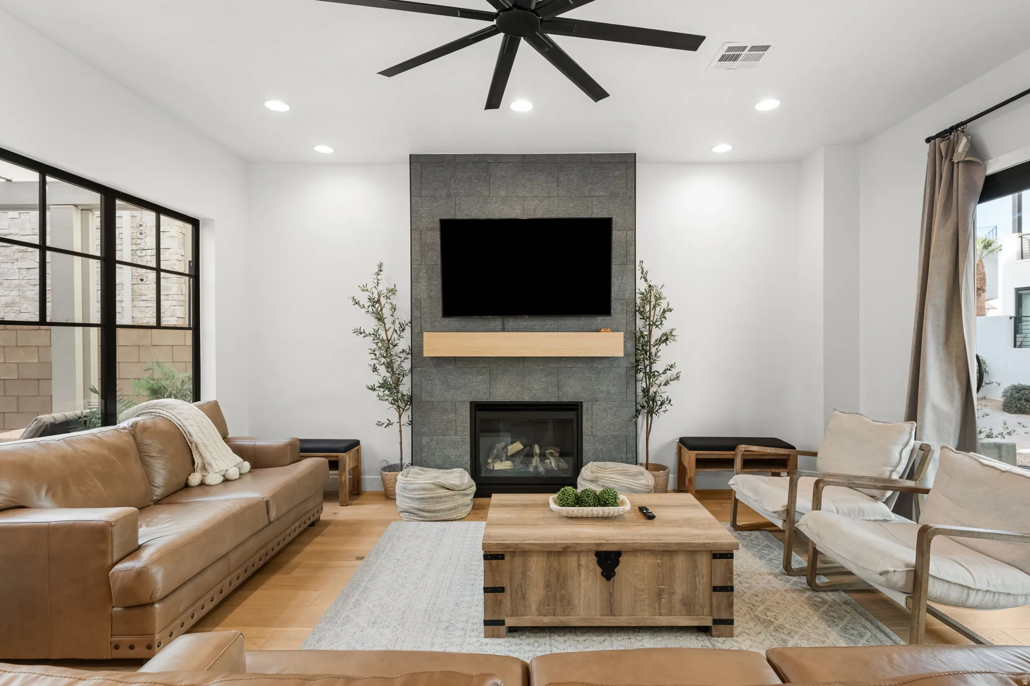 Living room with a ceiling fan, wood finished floors, a tile fireplace, and recessed lighting