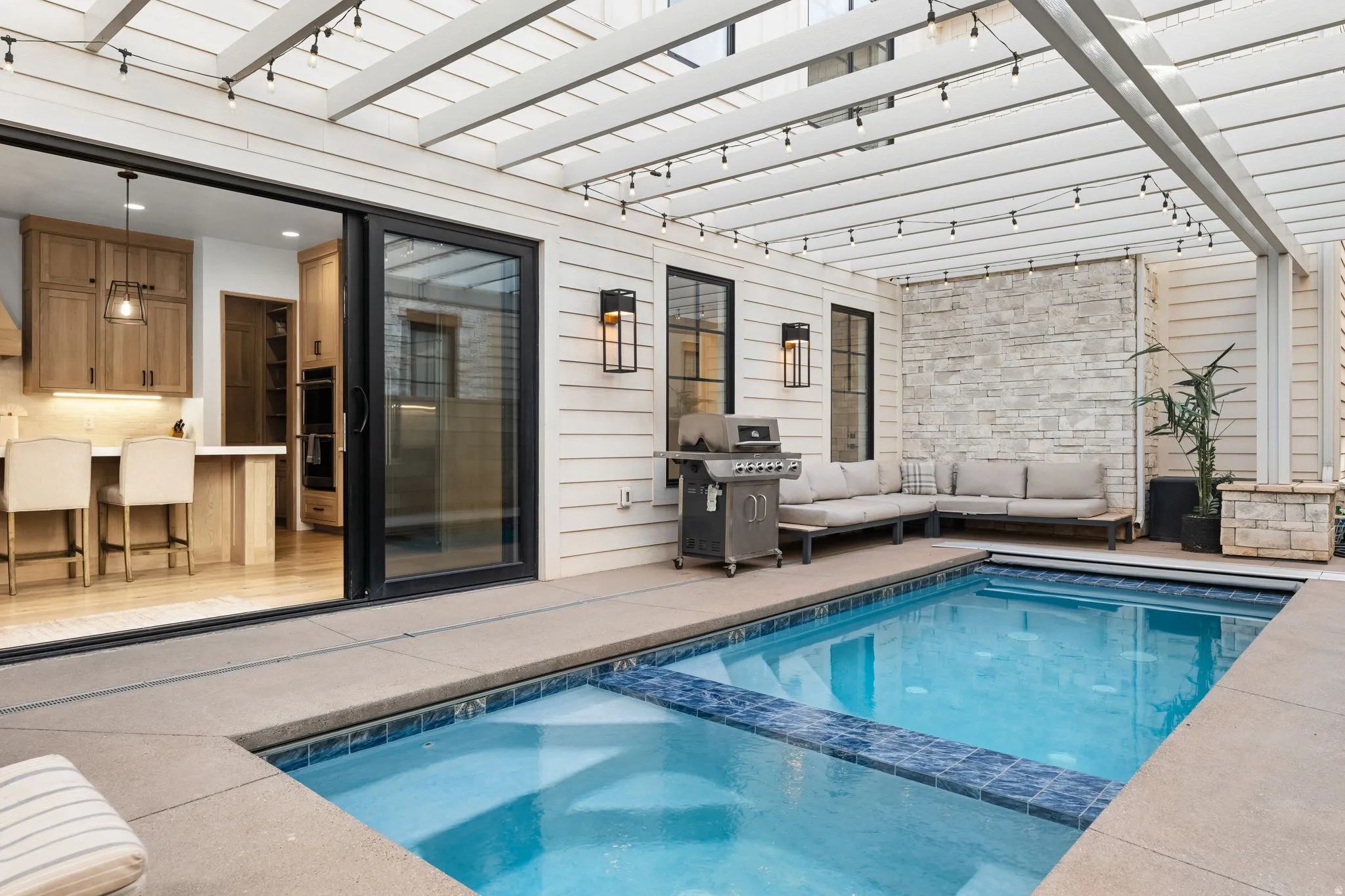 Combined pool / hot tub featuring area for grilling, a patio area, outdoor seating, and a pergola