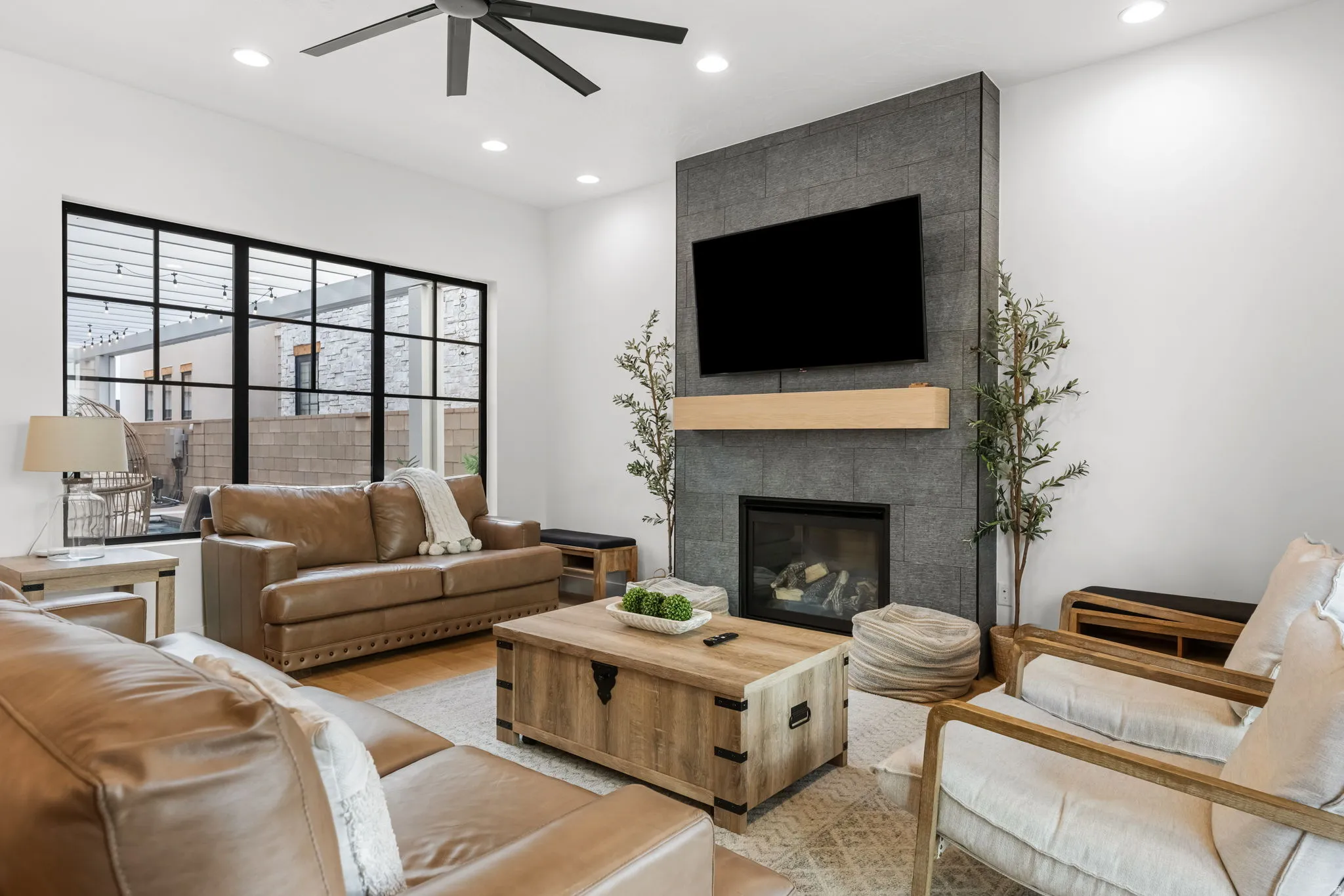 Living room with a tile fireplace, a ceiling fan, recessed lighting, and light wood-type flooring