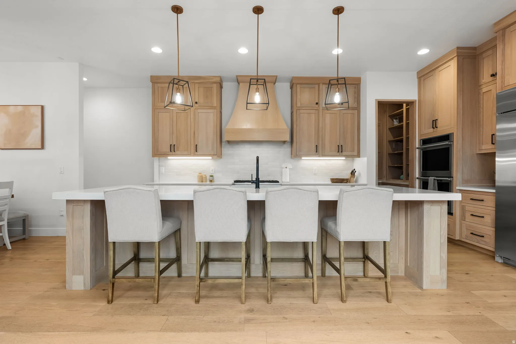 Kitchen with a kitchen bar, a spacious island, hanging light fixtures, and light wood-style flooring