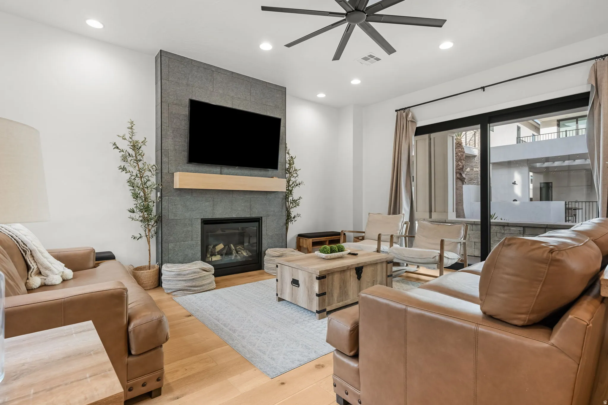 Living room featuring ceiling fan, a tile fireplace, light wood-type flooring, and recessed lighting