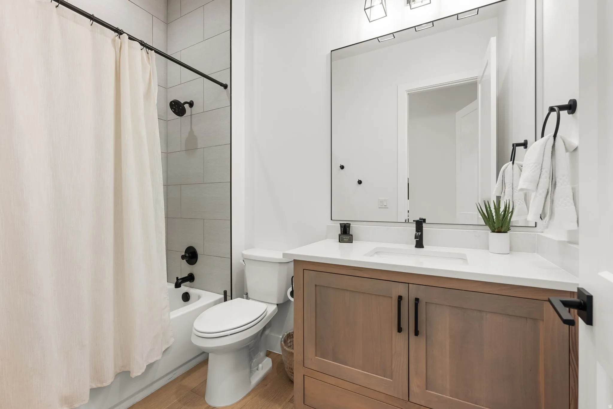 Bathroom featuring vanity, shower / bath combo, and light wood finished floors
