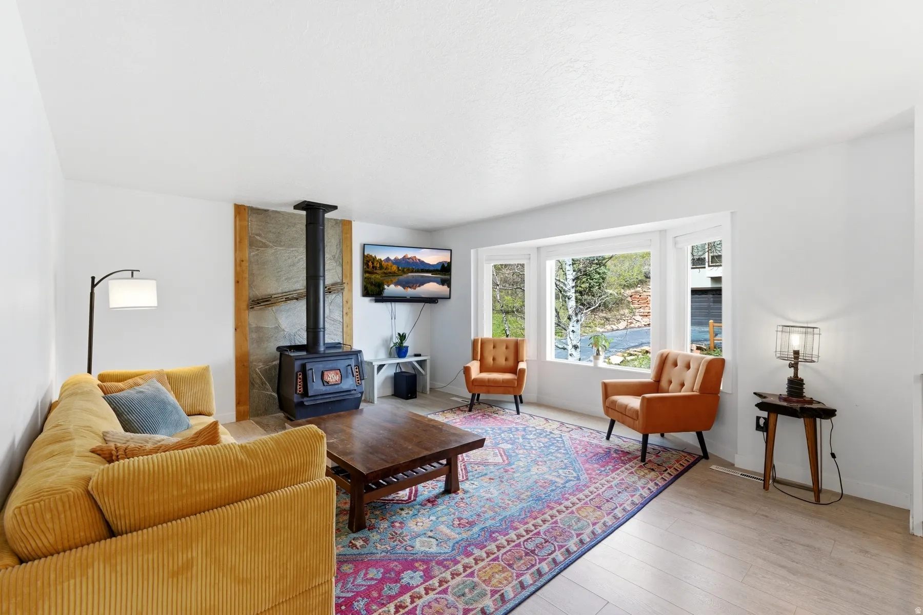 Living room with a wood stove and light wood-style flooring