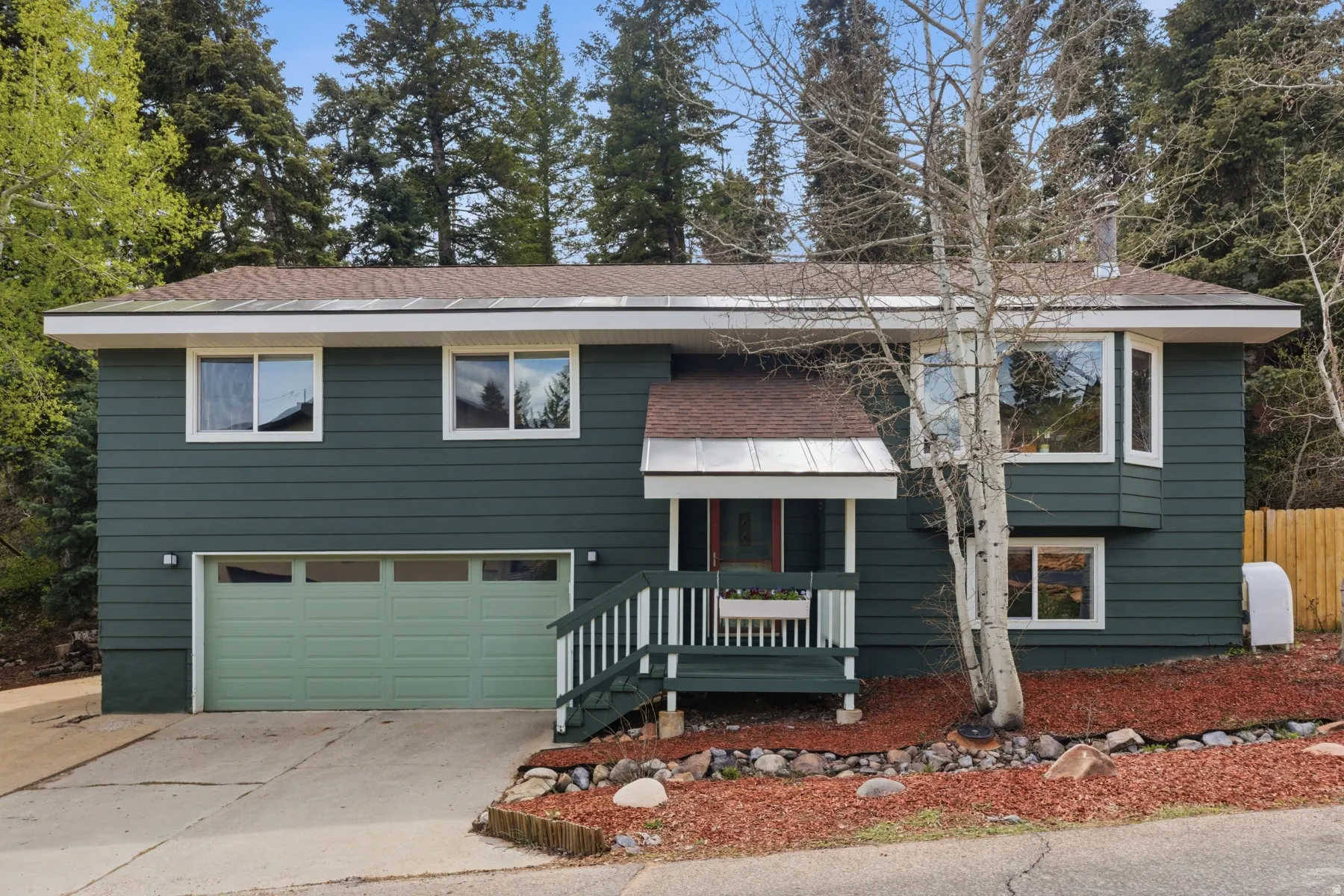 Bi-level home with a garage, a shingled roof, concrete driveway, heating fuel, and a porch