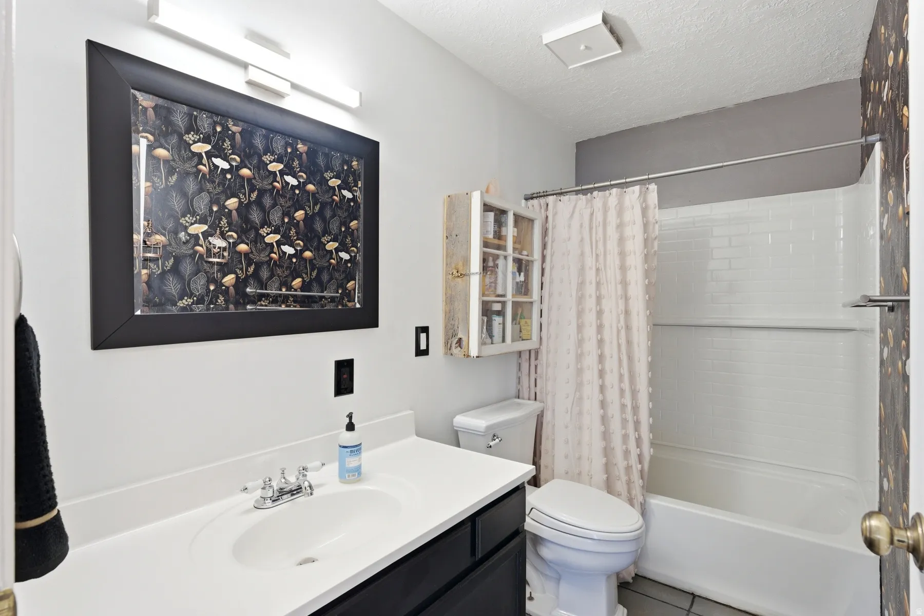Full bath featuring vanity, shower / bathtub combination with curtain, a textured ceiling, and tile patterned flooring