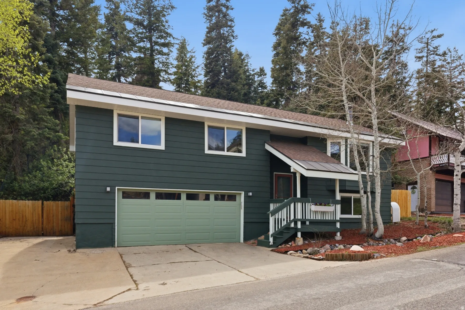 Split foyer home featuring an attached garage, roof with shingles, and concrete driveway