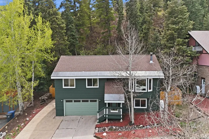 View of front of property featuring driveway, an attached garage, and a shingled roof
