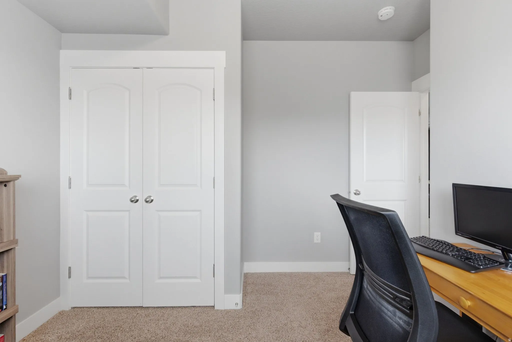 Bedroom/office space with light carpet and baseboards