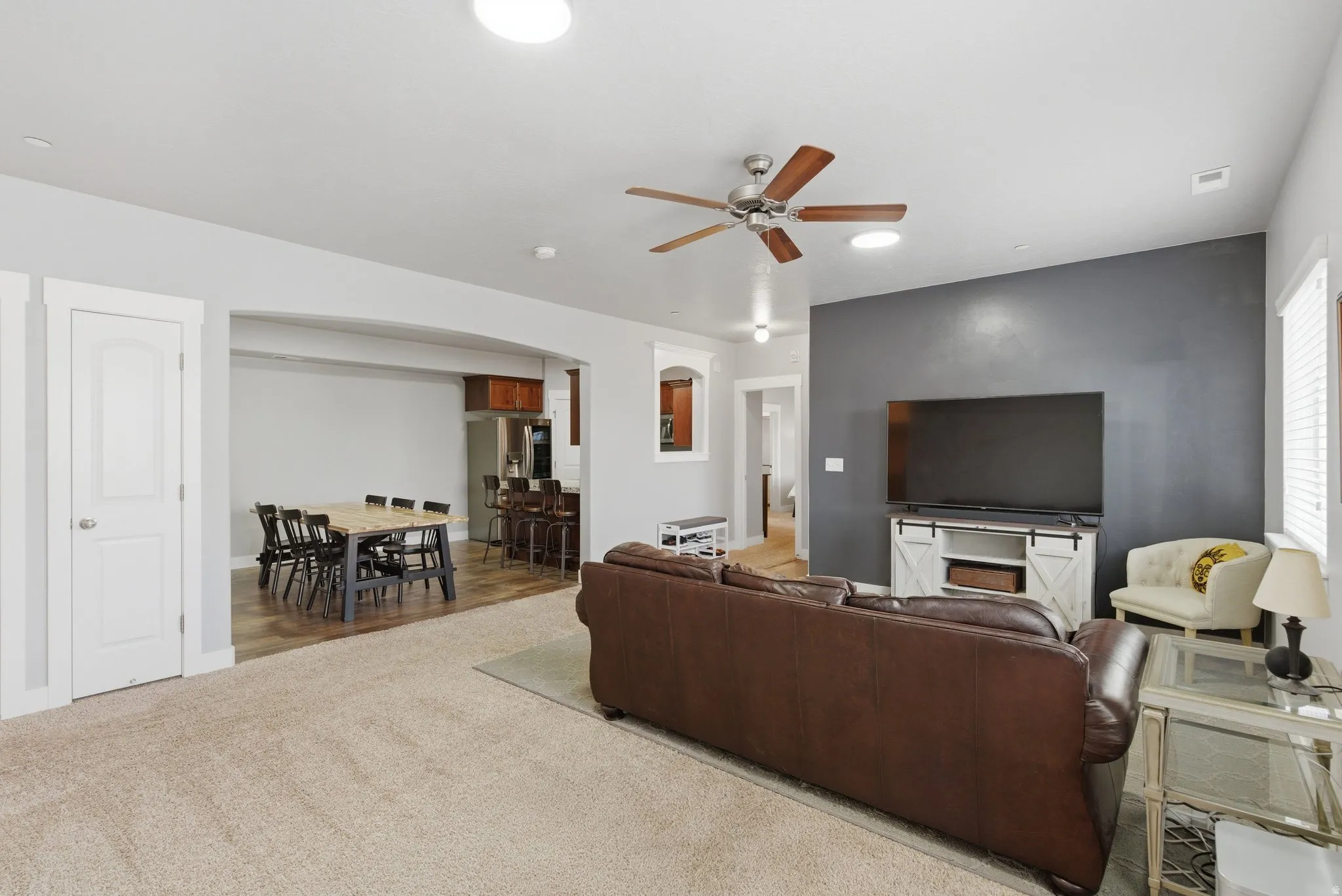 Living room featuring ceiling fan, carpet, arched walkways, and recessed lighting