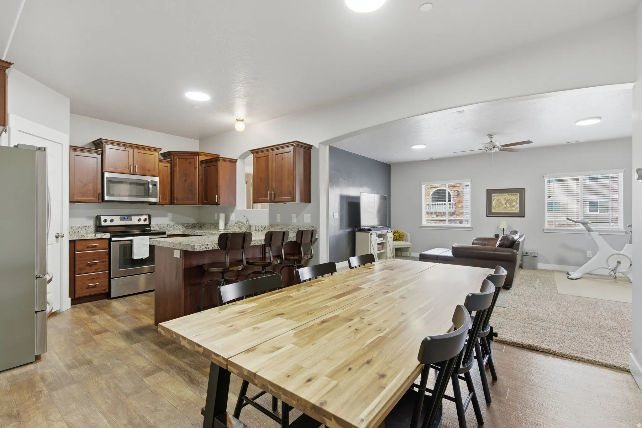 Dining area with arched walkways, light wood finished floors, a ceiling fan, and recessed lighting