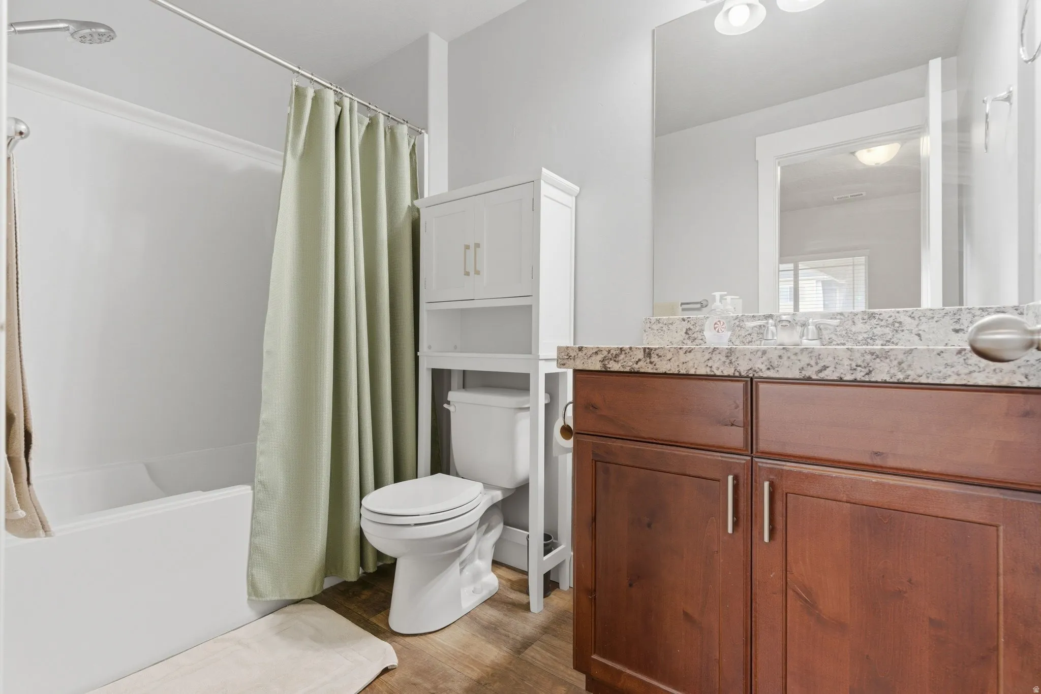 Full bath featuring vanity, shower / bath combo with shower curtain, and dark wood-style floors