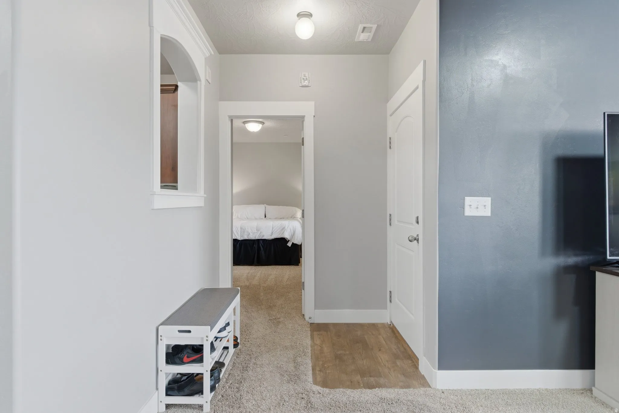 Hallway with light wood-type flooring, a textured ceiling, and light colored carpet