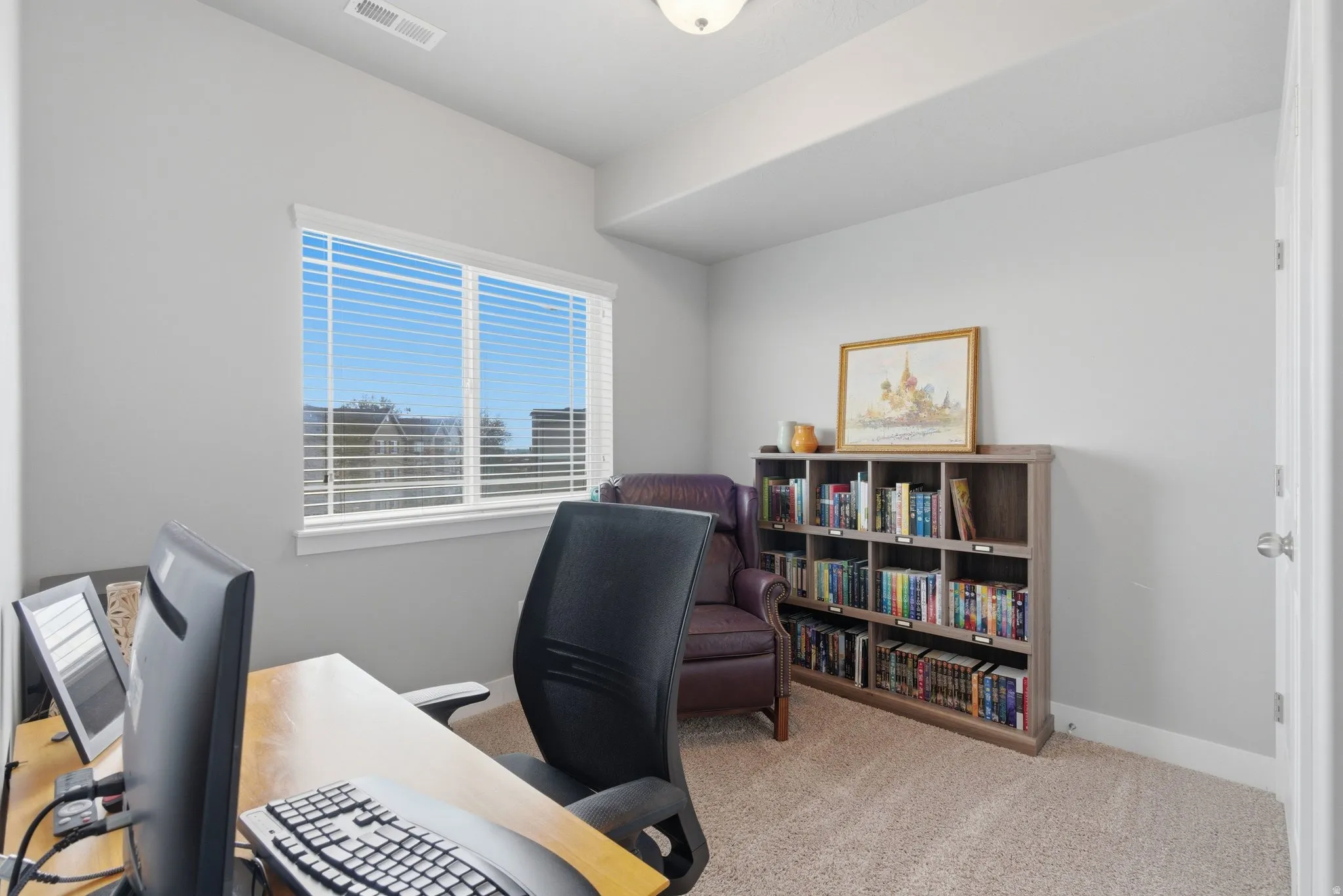 Bedroom/office space with light carpet and baseboards