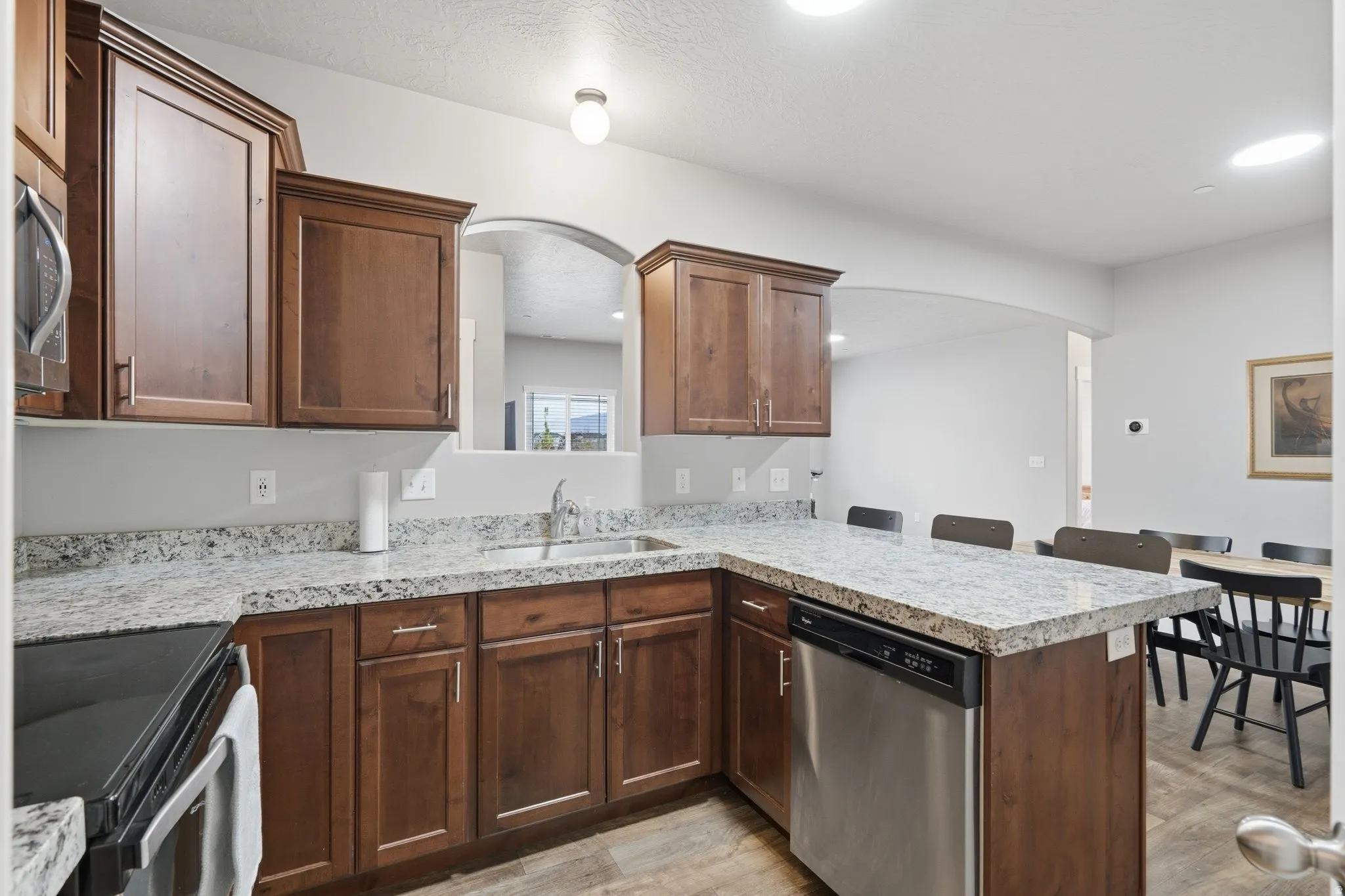 Kitchen featuring a peninsula, stainless steel appliances, arched walkways, light countertops, and a breakfast bar area