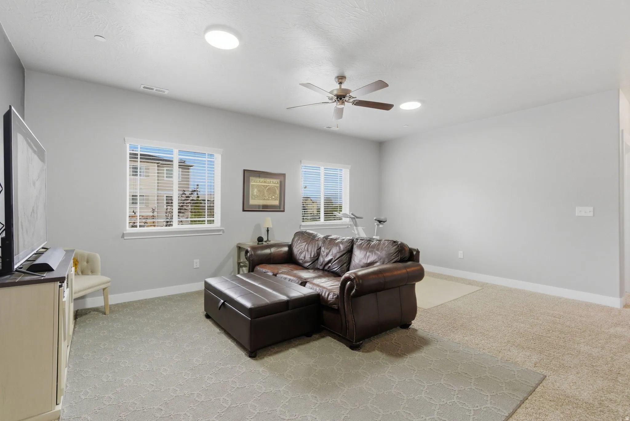 Living room featuring light colored carpet and a ceiling fan