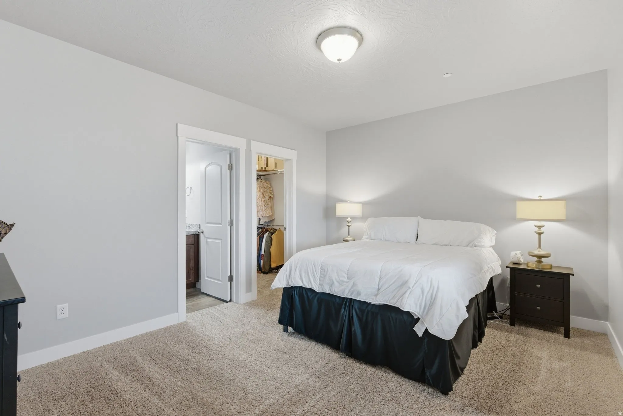 Bedroom featuring a spacious closet, light colored carpet, and ensuite bathroom
