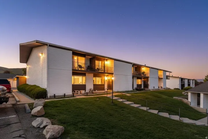 Back of property at dusk with a balcony and a yard
