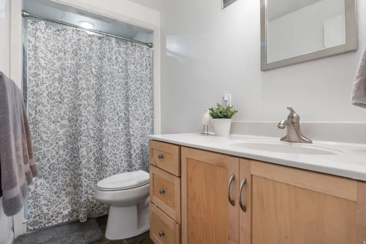 Bathroom with vanity, a shower with curtain, and a textured wall