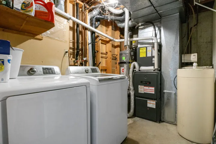 Laundry area with concrete flooring, washing machine and clothes dryer, and water heater