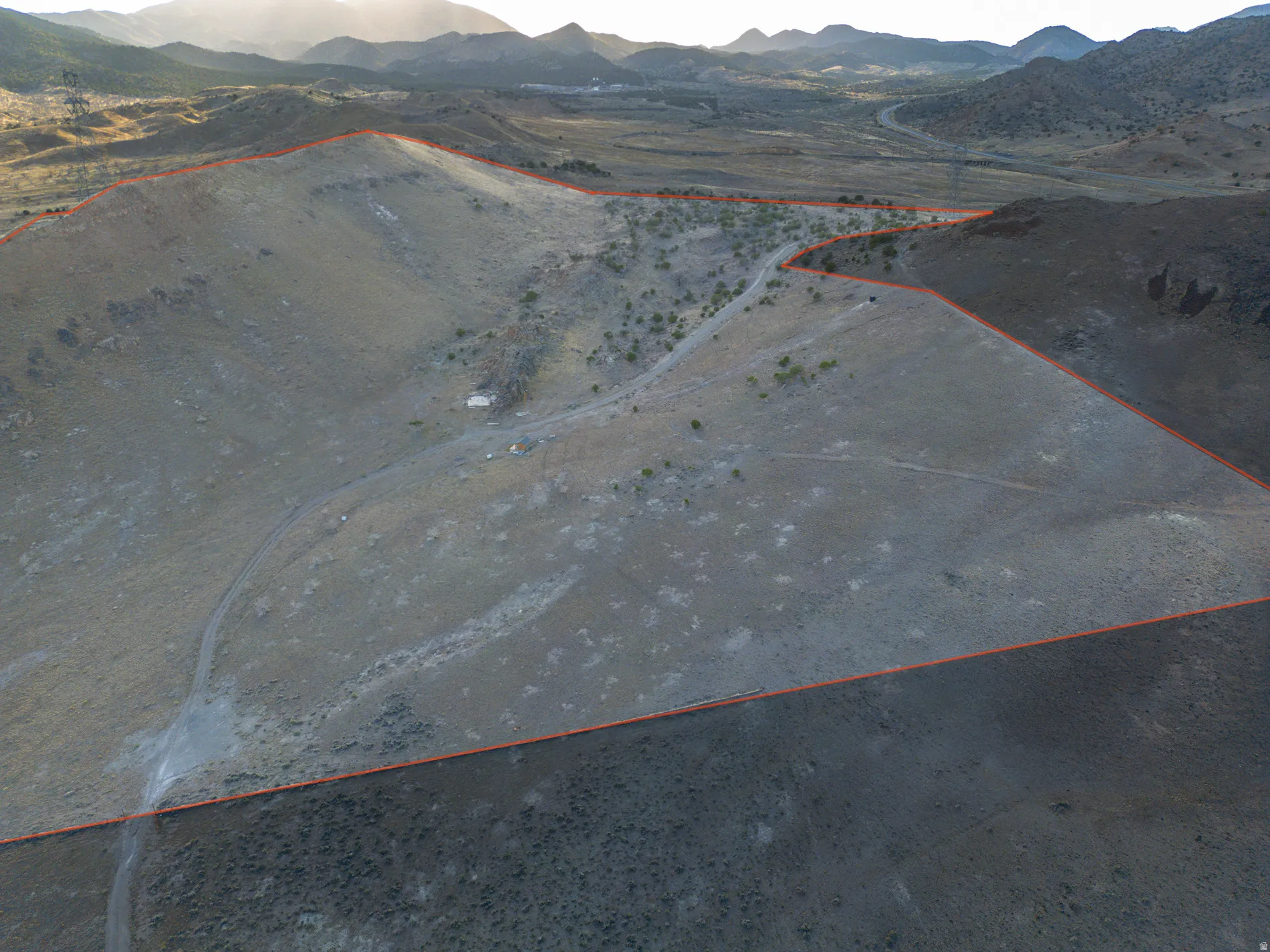 Aerial overview of property's location with a mountainous background and property boundaries highlighted