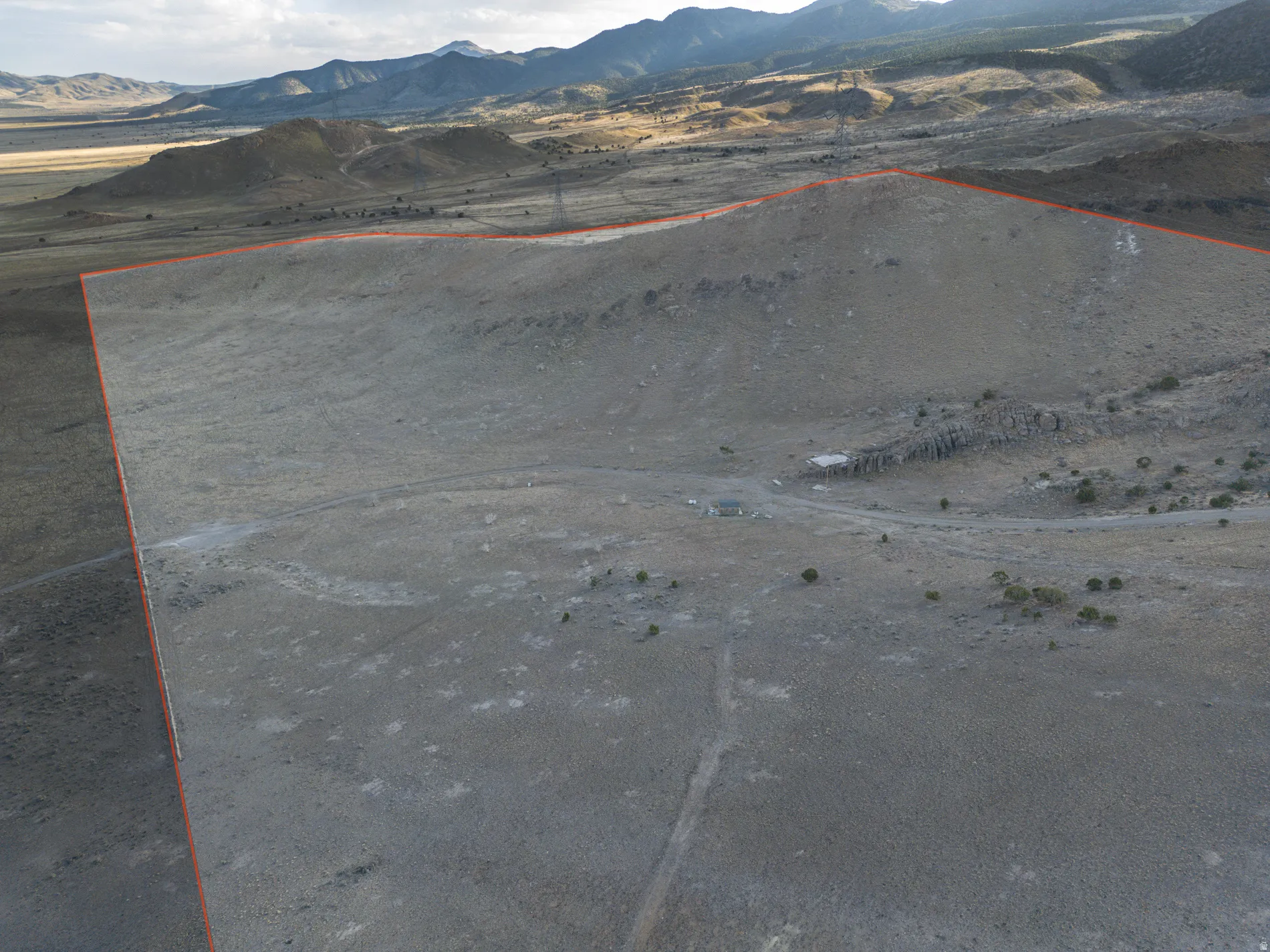 Aerial view of sparsely populated area with a mountain backdrop and property parcel outlined