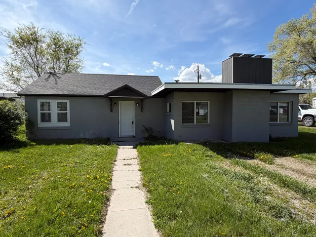 View of front of house with a front lawn, a chimney, roof with shingles, and brick siding