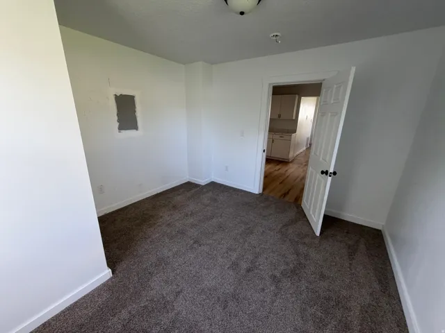 Empty room featuring dark carpet and baseboards