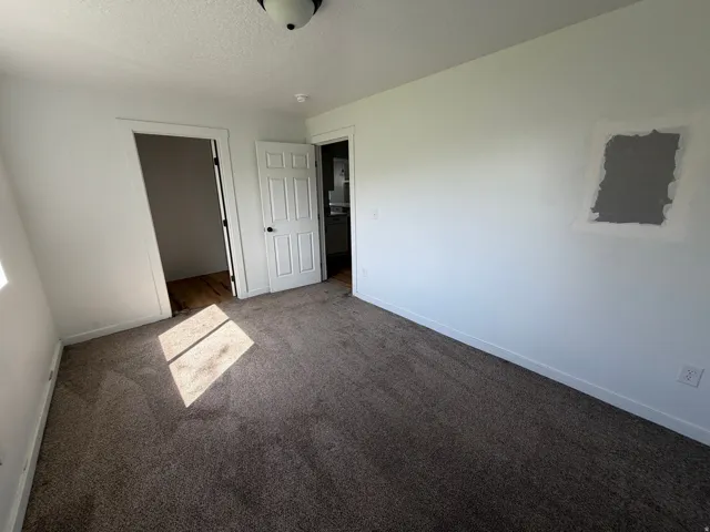 Unfurnished bedroom with dark colored carpet, a textured ceiling, and a walk in closet